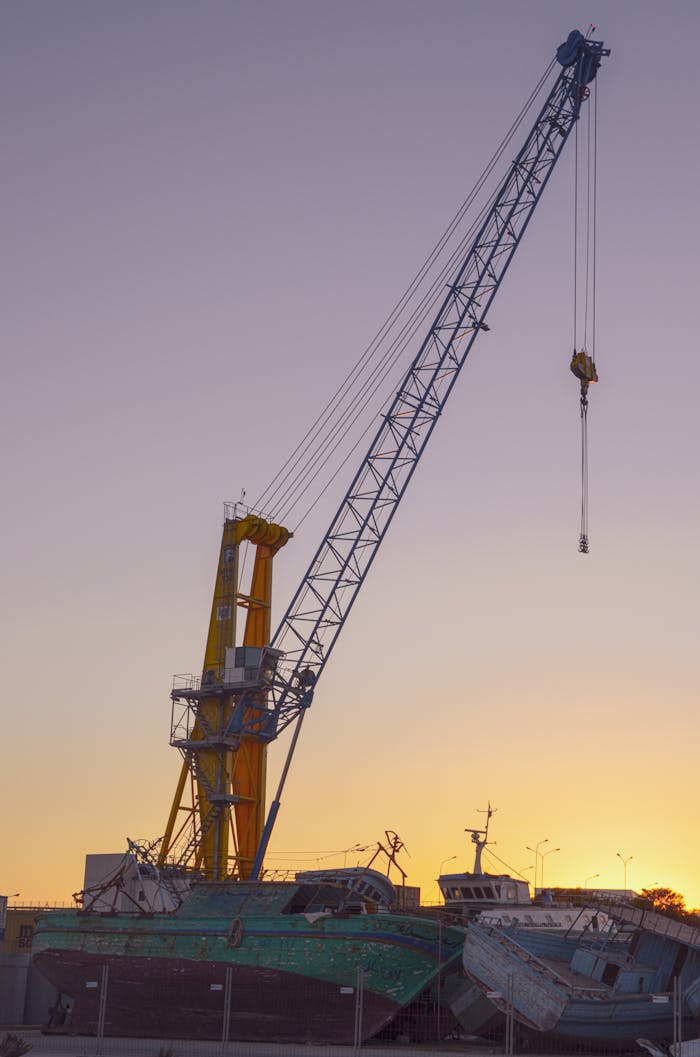 Home A dramatic harbor crane silhouetted against a vivid sunset sky, symbolizing industrial strength.