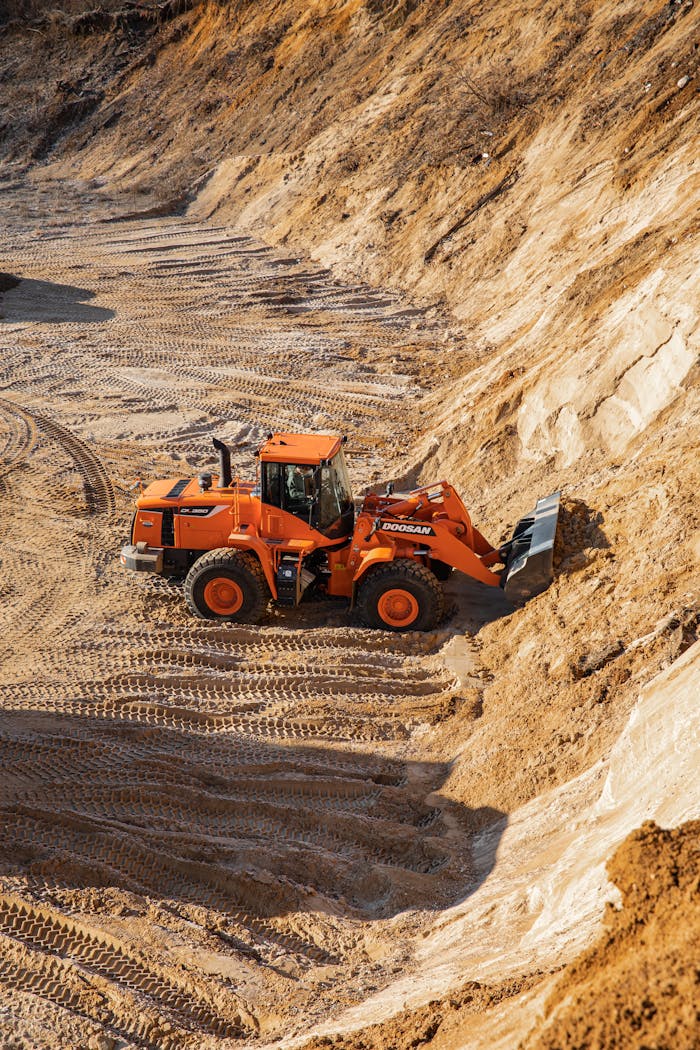 Home High-angle shot of an orange wheel loader working on a sandy construction site.