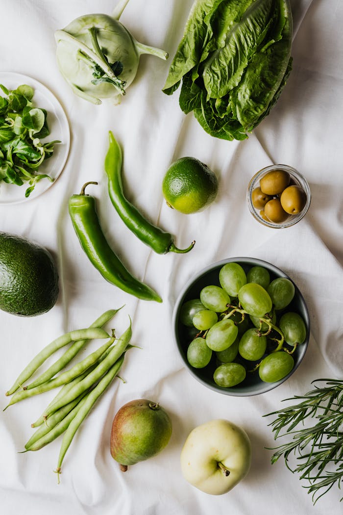 A selection of fresh green fruits and vegetables arranged on a white background.