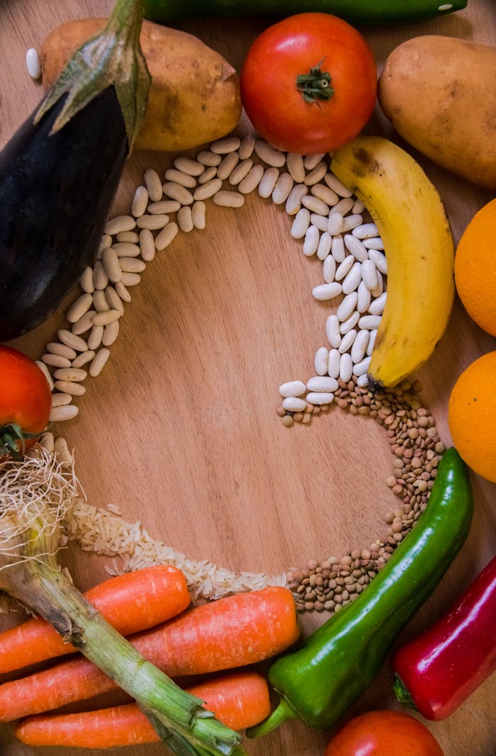 An artistic arrangement of fresh fruits and vegetables on a wooden table in a studio setting.