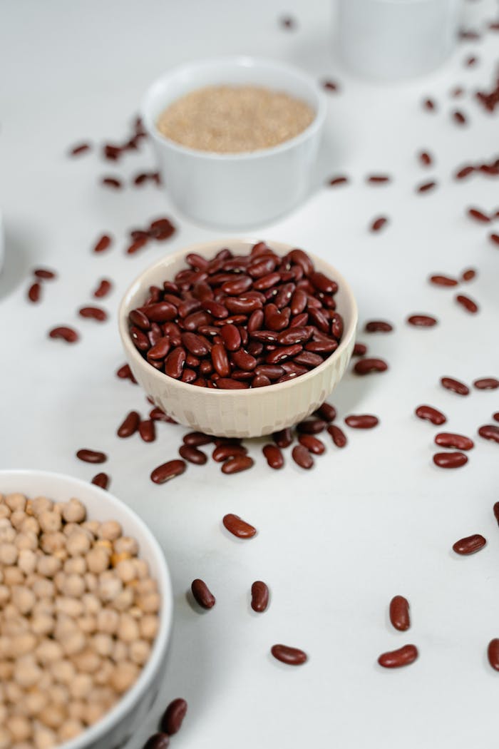 About Aerial view of various uncooked beans in ceramic bowls on a white surface.